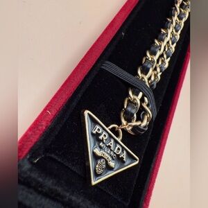 Prada black metal label on a silver colored chain